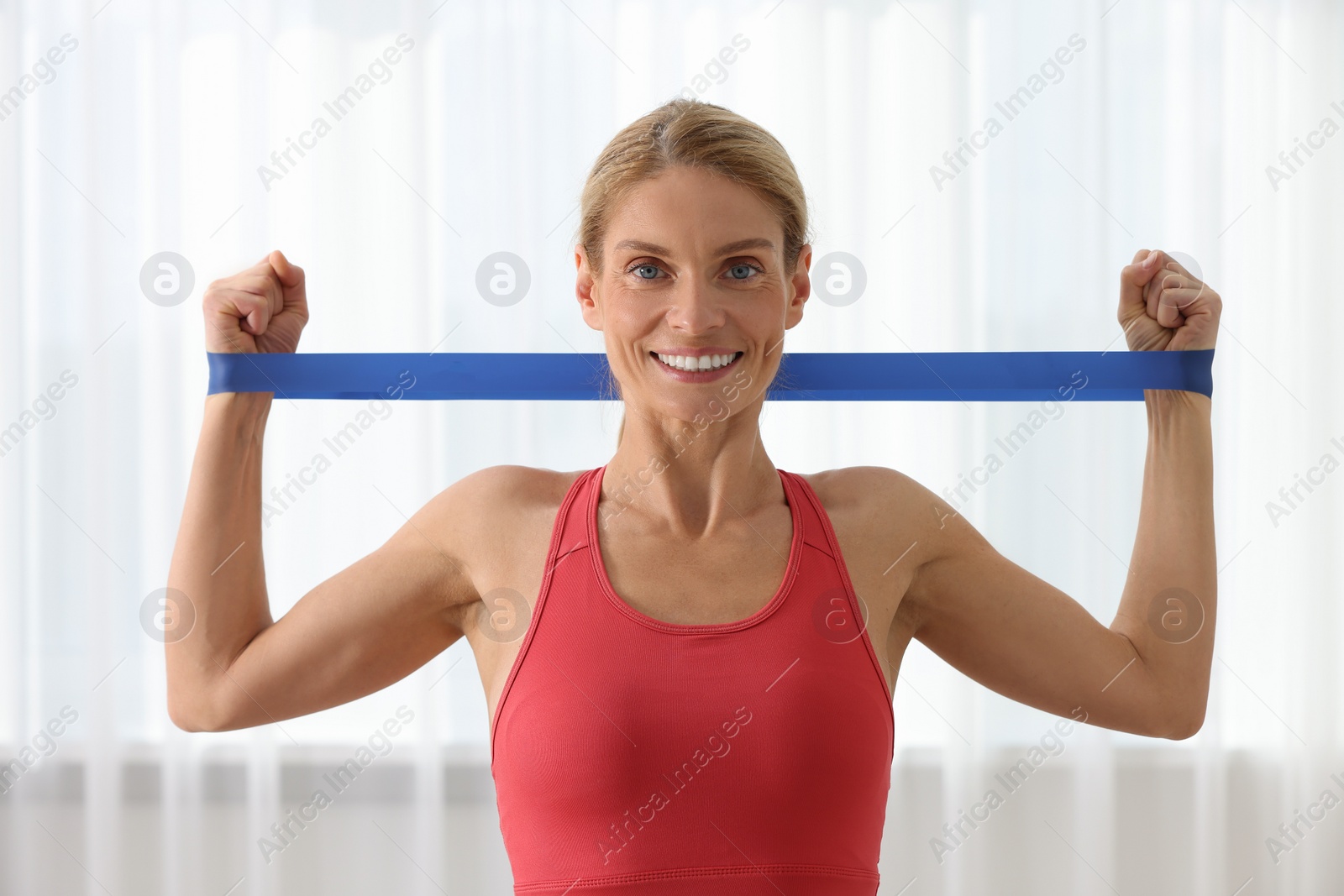 Photo of Fit woman doing exercise with fitness elastic band indoors