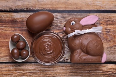 Flat lay composition with chocolate Easter bunny, egg and candies on wooden table