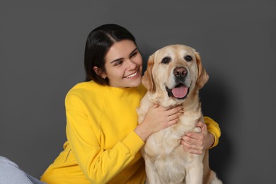 Photo of Happy woman with cute Labrador Retriever against grey wall