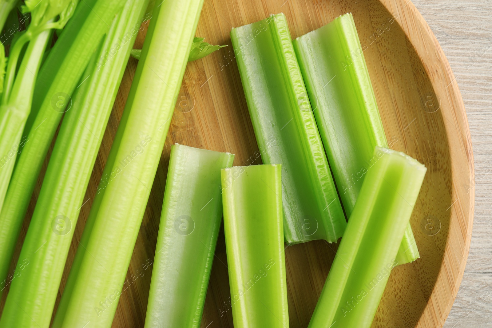 Photo of Fresh cut celery stalks on wooden table, top view
