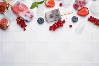 Flat lay composition with berry ice pops on white table. Space for text