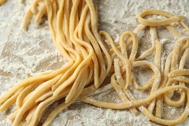 Photo of Raw homemade pasta and flour on table, closeup