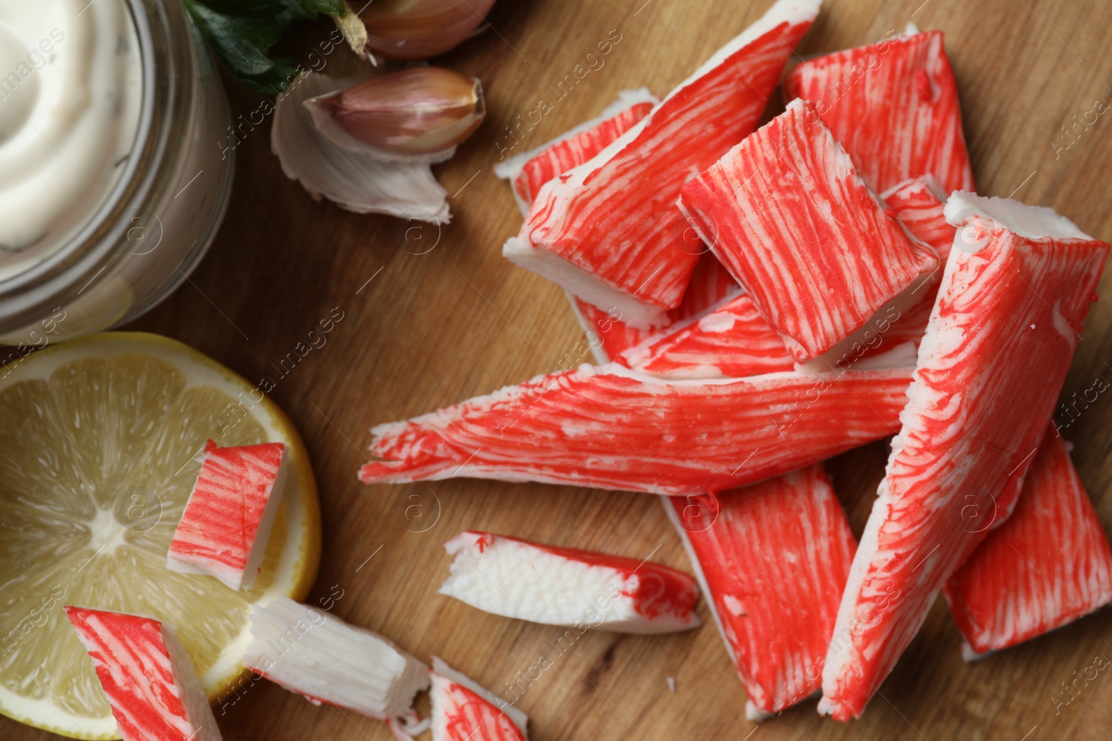 Photo of Delicious crab sticks served on wooden board, closeup