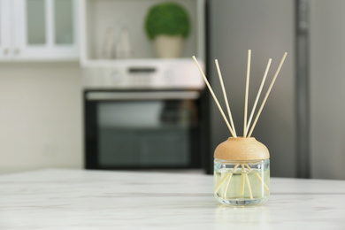 Photo of Aromatic reed air freshener on white marble table indoors. Space for text