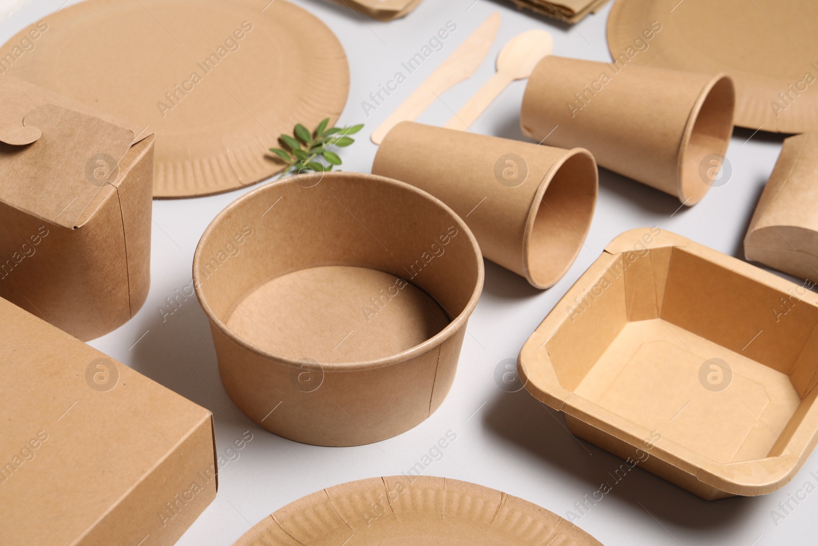 Photo of Eco friendly food packaging. Paper containers, tableware and green twigs on light grey background