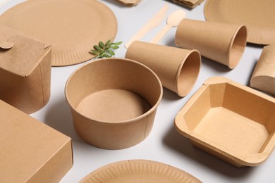 Eco friendly food packaging. Paper containers, tableware and green twigs on light grey background