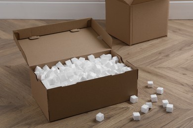 Cardboard box and styrofoam cubes on wooden floor indoors