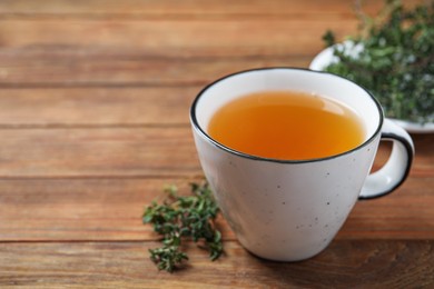 Photo of Aromatic herbal tea with thyme on wooden table, closeup. Space for text