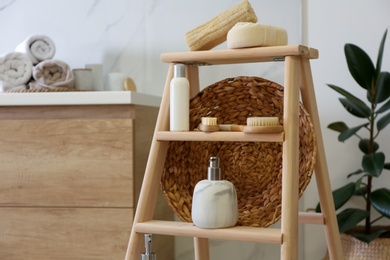 Dispensers and different toiletries on decorative ladder in bathroom, closeup. Idea for interior design