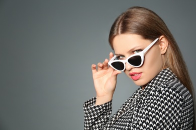Photo of Young woman wearing stylish sunglasses on grey background. Space for text