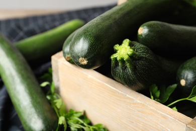 Photo of Raw green zucchinis in wooden crate, closeup