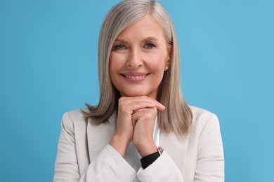 Photo of Portrait of beautiful middle aged woman on light blue background