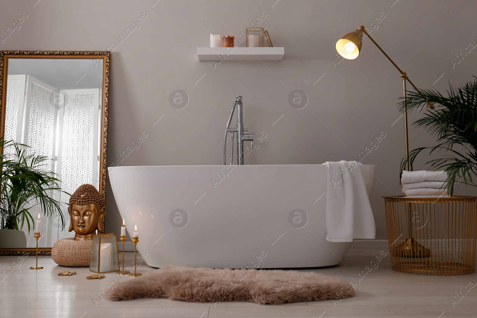 Photo of Bathroom interior with golden Buddha sculpture and modern white tub