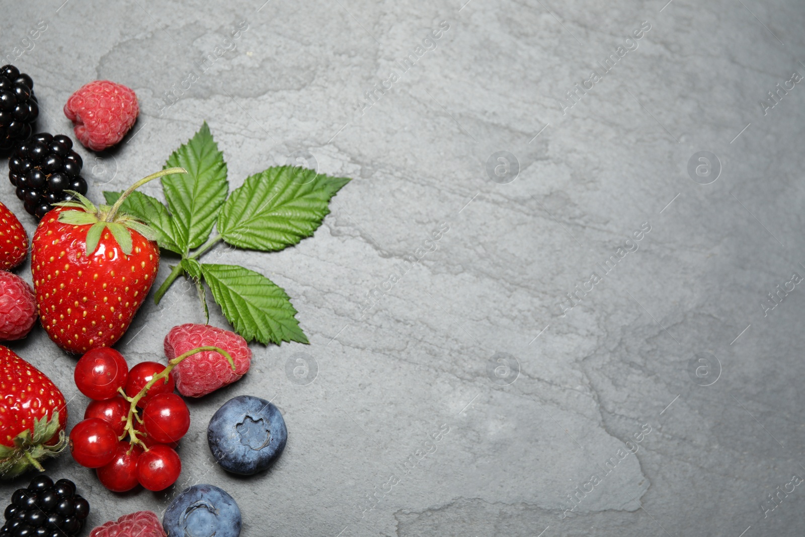 Photo of Different fresh berries on grey background, flat lay. Space for text