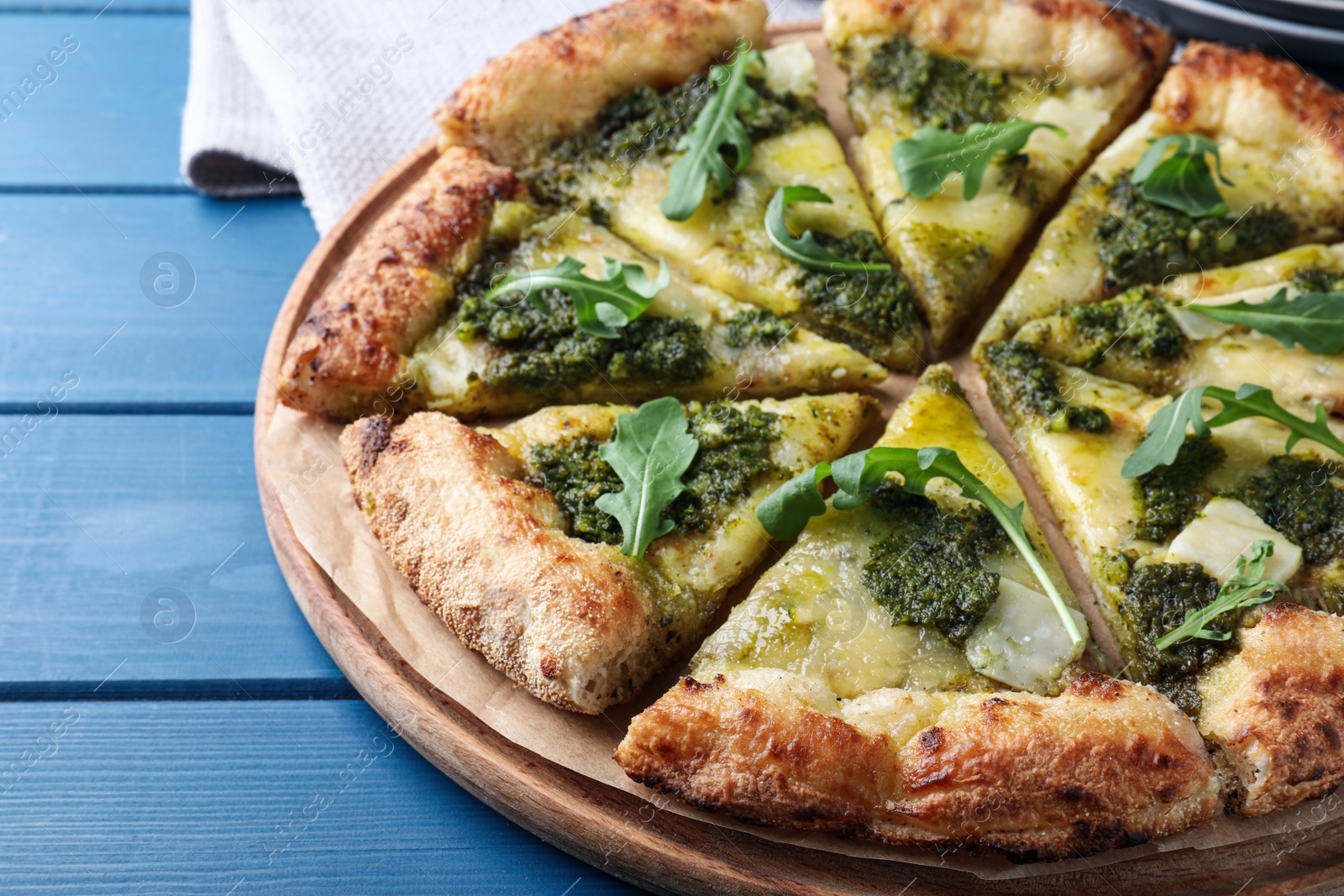 Photo of Delicious pizza with pesto, cheese and arugula on blue wooden table, closeup