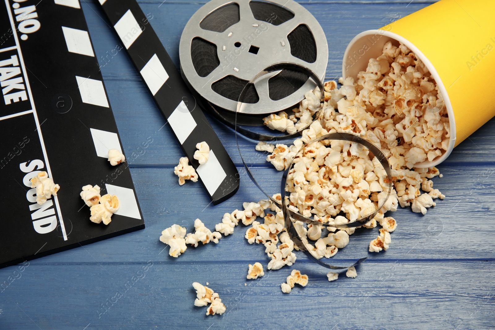 Photo of Composition with popcorn, film reel and clapperboard on wooden background