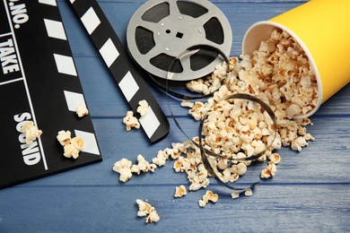 Composition with popcorn, film reel and clapperboard on wooden background