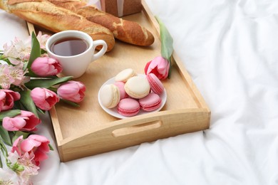 Photo of Delicious breakfast and flowers on bed. Space for text