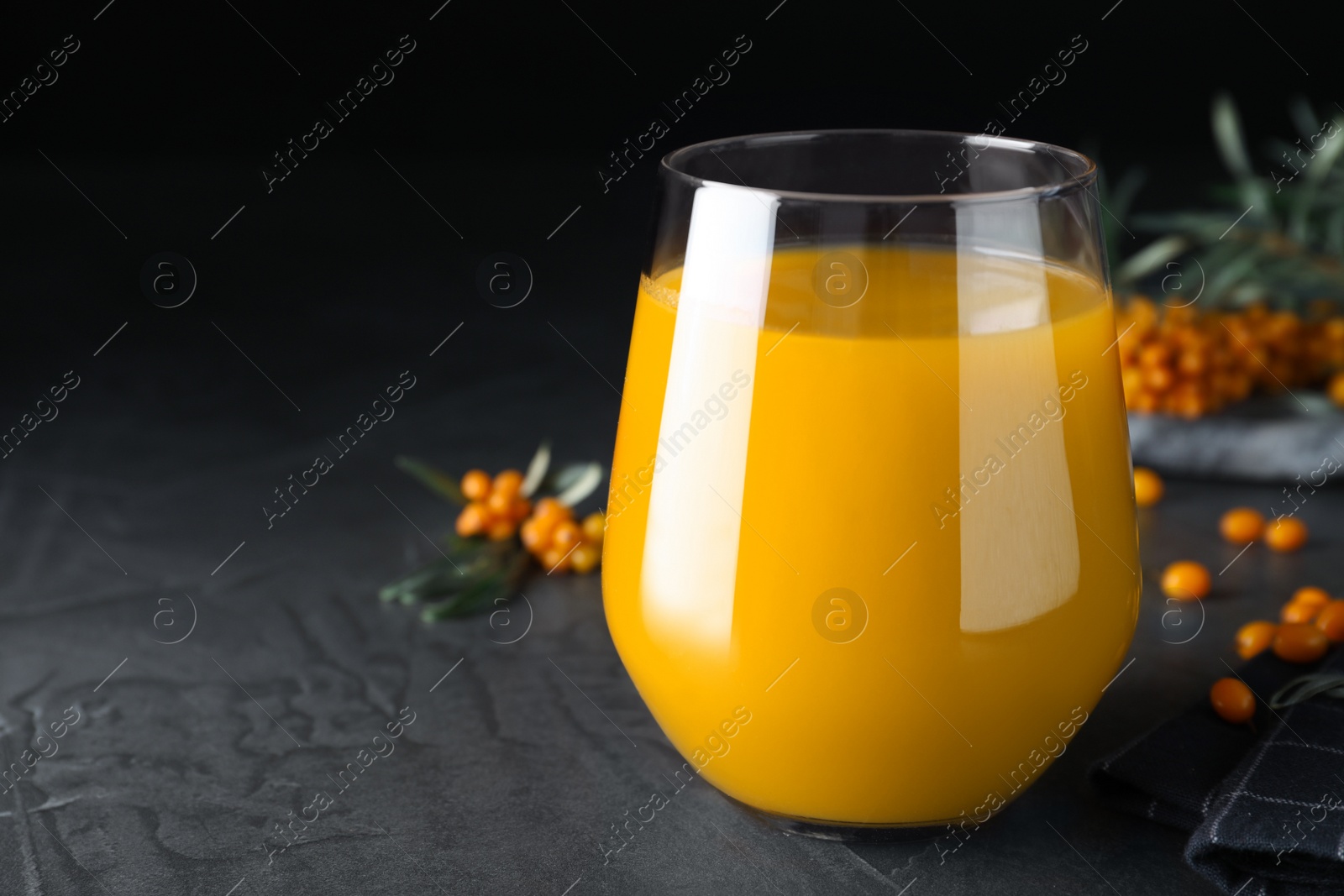 Photo of Sea buckthorn juice on black table, closeup. Space for text