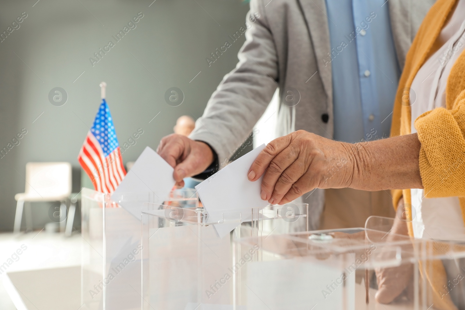 Photo of Elderly people putting ballot papers into boxes at polling station, closeup