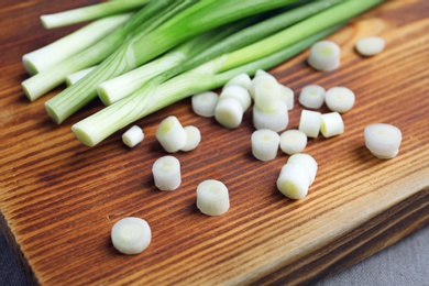 Photo of Wooden board with fresh green onion, closeup