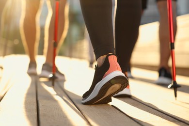 Photo of Group of people practicing Nordic walking with poles outdoors on sunny day, closeup