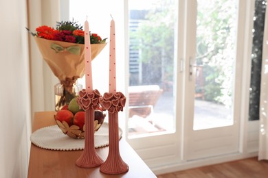 Photo of Bouquet of flowers, bowl with fresh fruits and candles on wooden table indoors. Space for text
