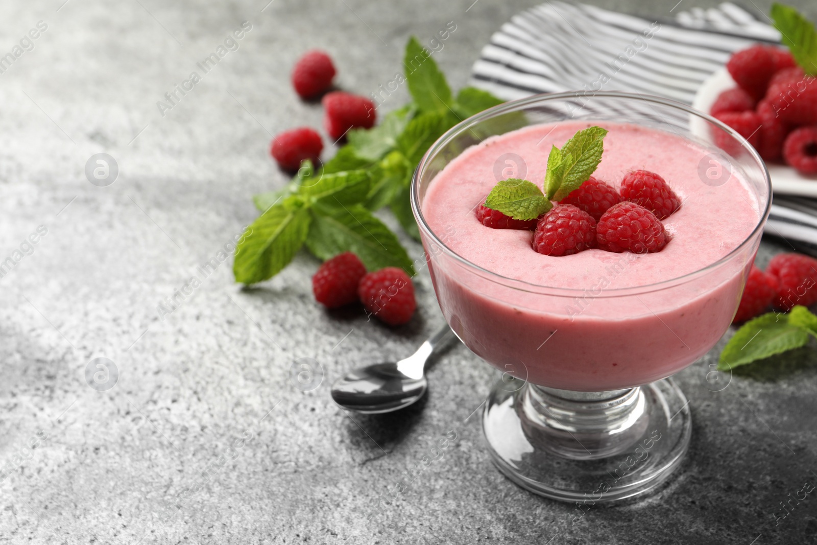 Photo of Delicious raspberry mousse with mint on grey table, space for text