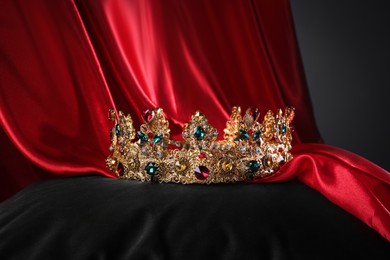 Beautiful golden crown with gems on black pillow