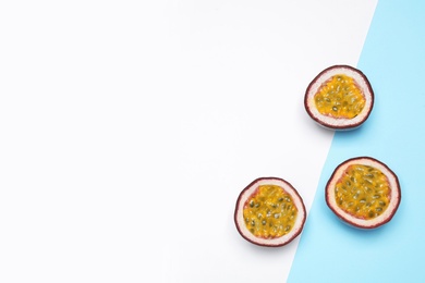 Photo of Halves of fresh ripe passion fruits (maracuyas) on color background, flat lay. Space for text