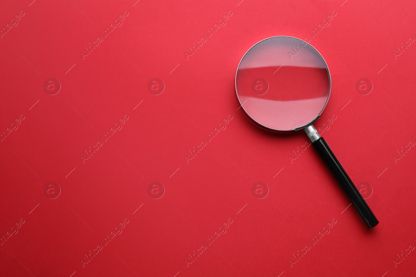 Photo of Magnifying glass on red background, top view. Space for text