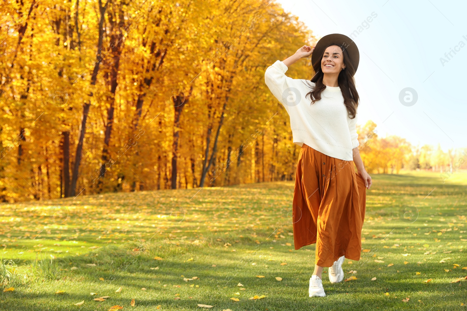 Photo of Beautiful happy woman wearing hat walking in autumn park