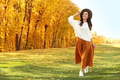 Beautiful happy woman wearing hat walking in autumn park
