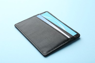 One leather business card holder with cards on light blue background