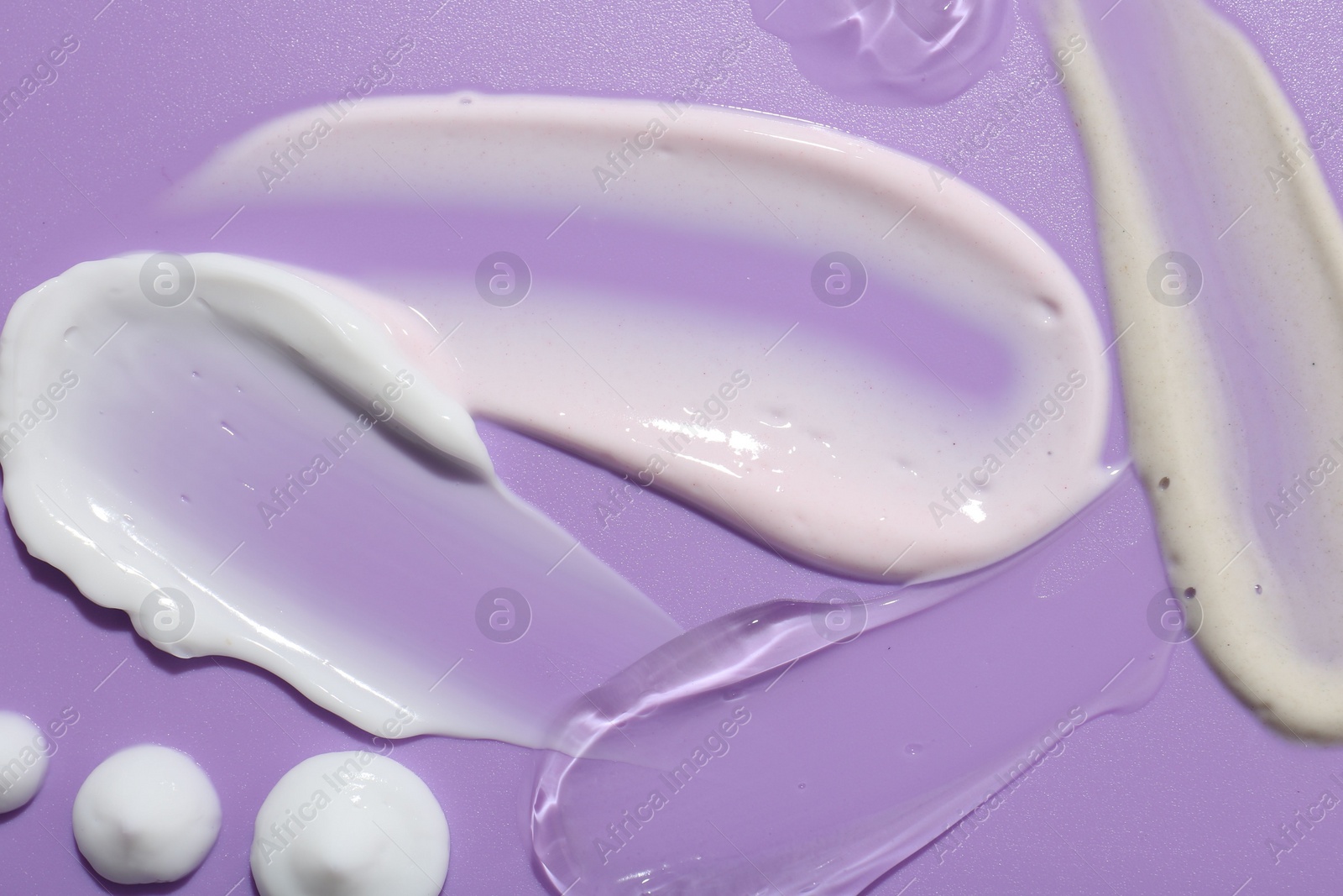 Photo of Samples of face cream on violet background, top view