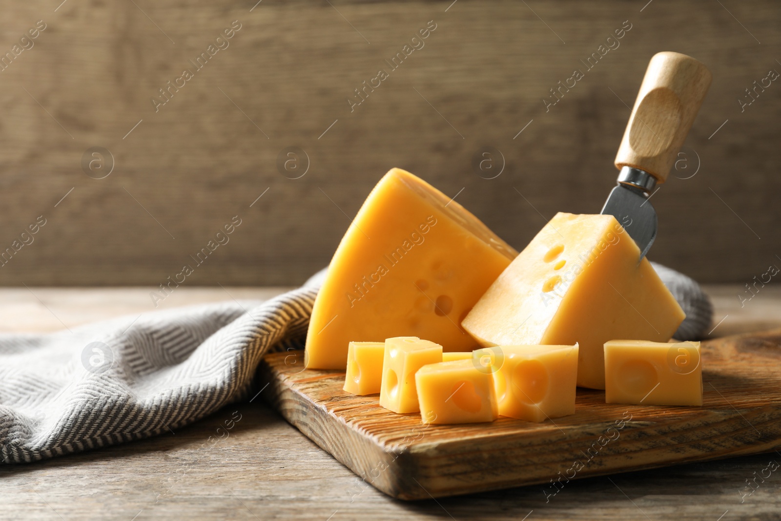 Photo of Serving board with delicious cheese on wooden table, space for text