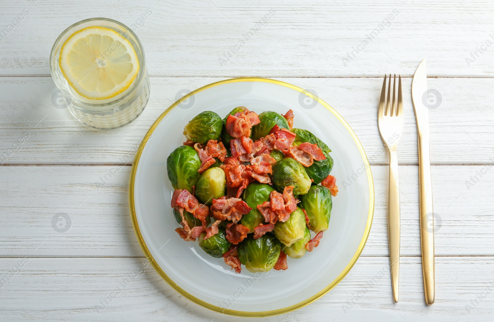 Photo of Flat lay composition of tasty roasted Brussels sprouts with bacon on white wooden table