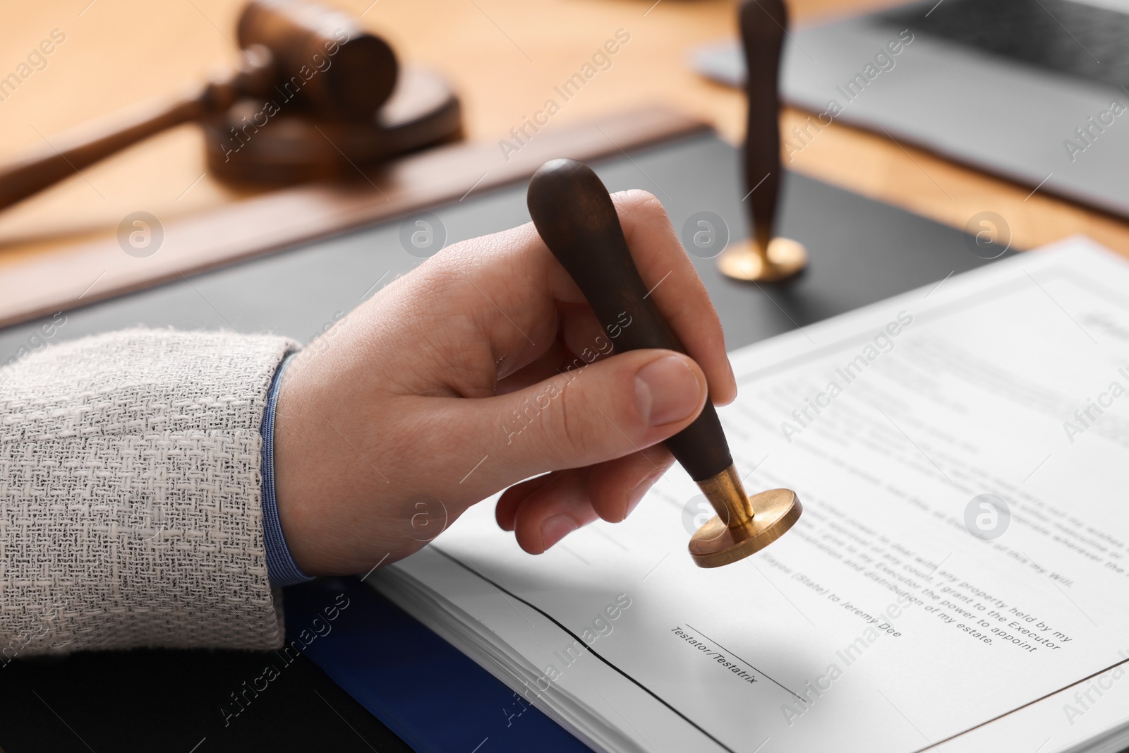 Photo of Notary stamping document at table, closeup view