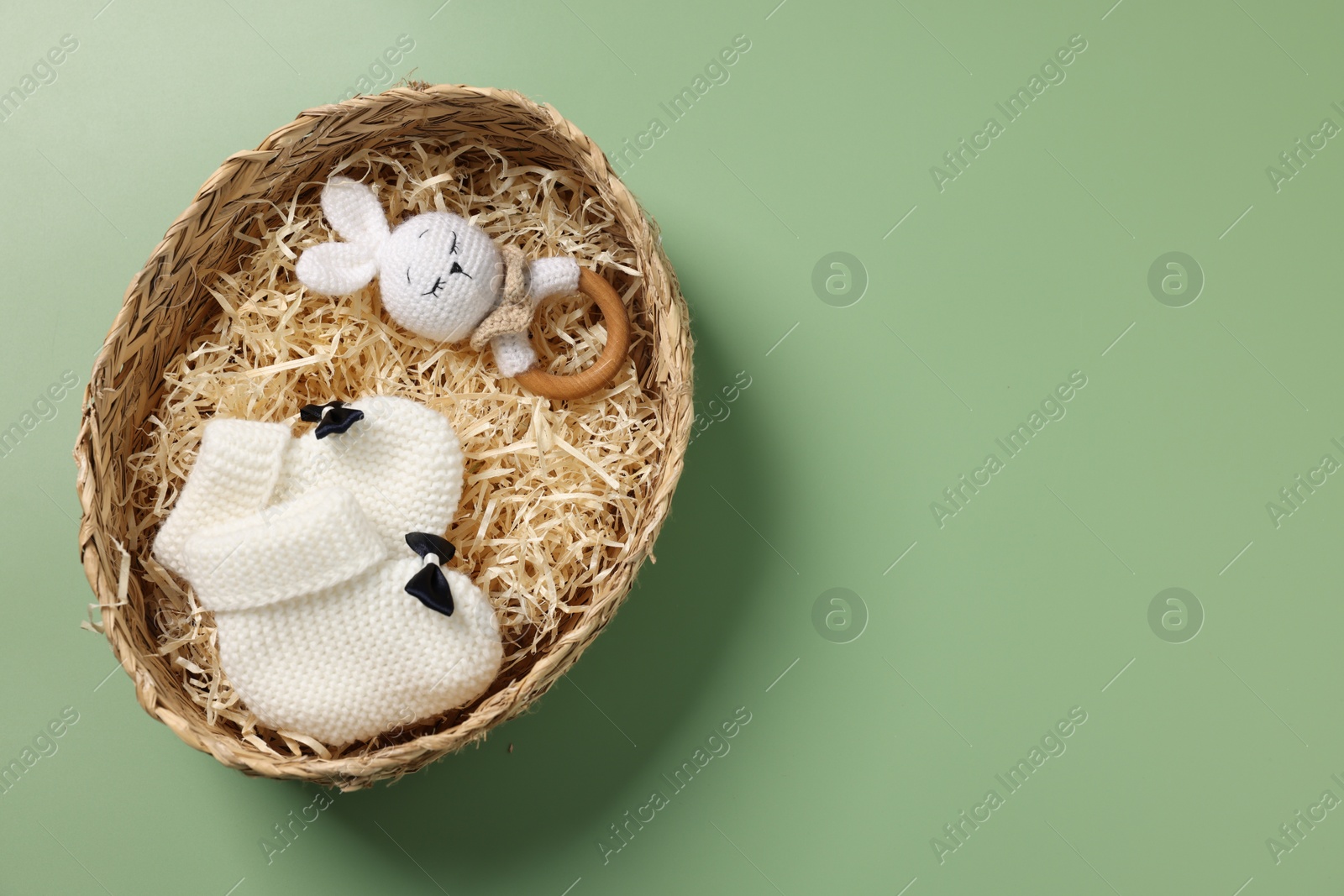 Photo of Different baby accessories in wicker box on green background, top view. Space for text