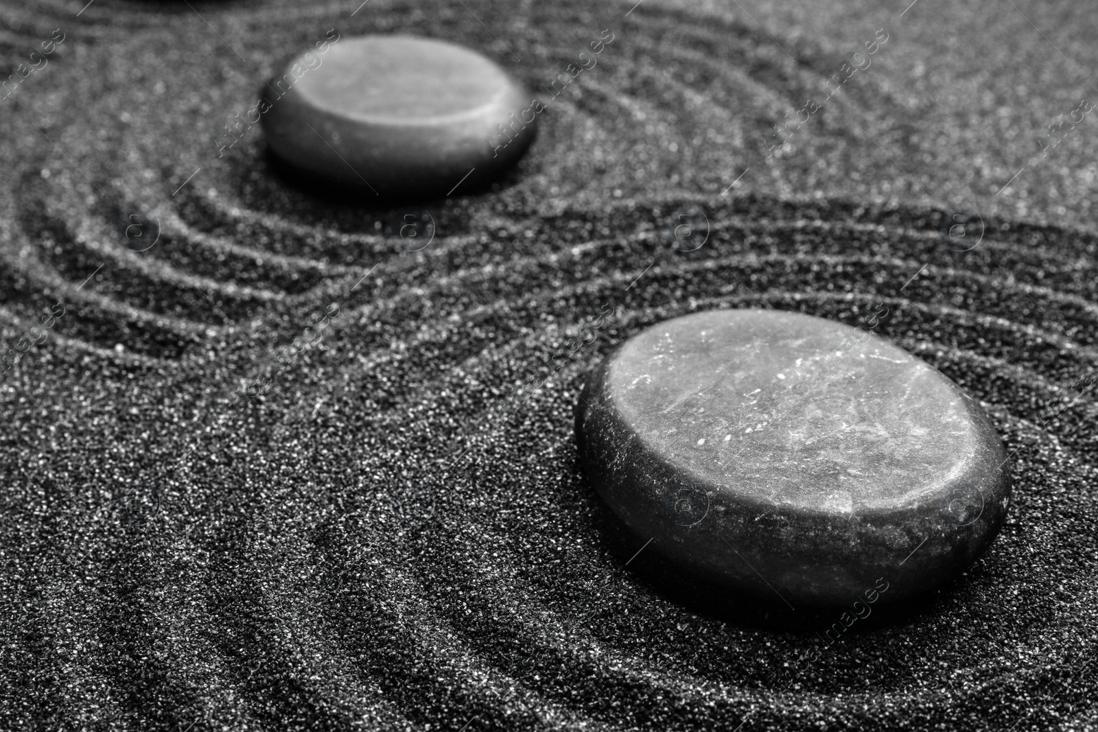 Photo of Black sand with stones and beautiful pattern. Zen concept