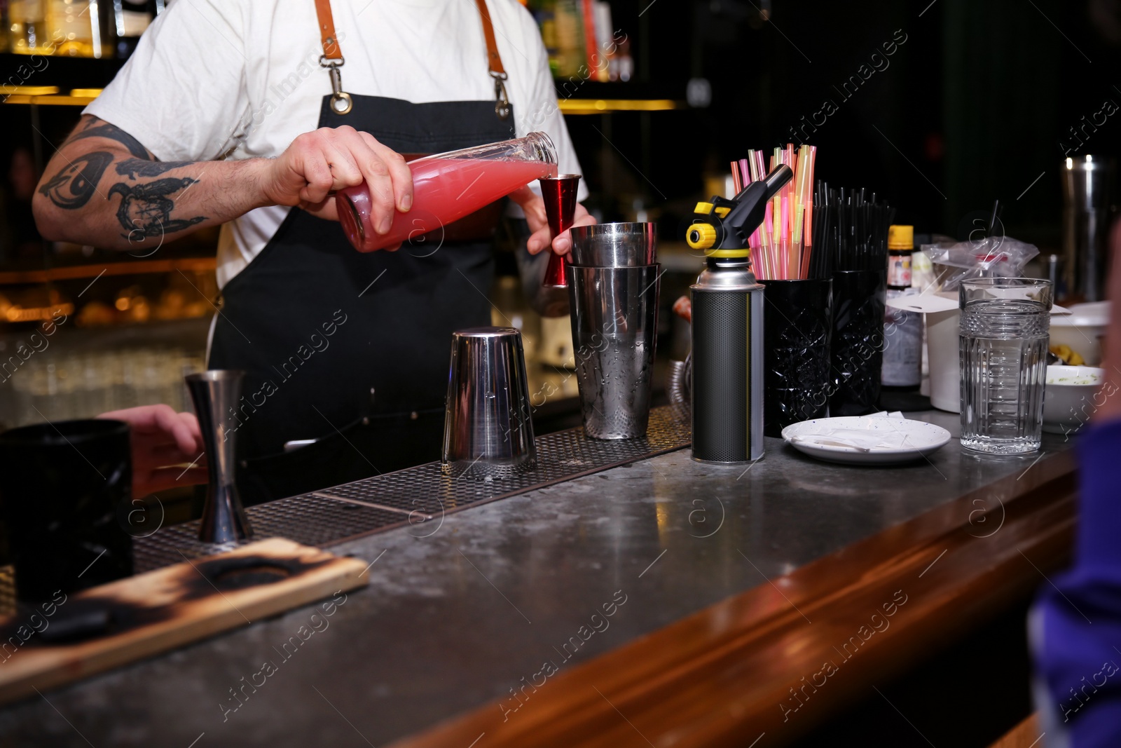 Photo of Bartender preparing tasty cocktail at counter in nightclub, closeup