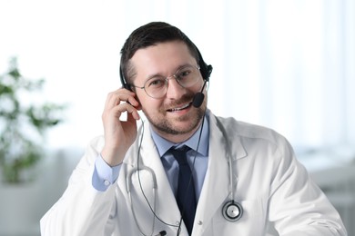 Smiling doctor in headset having online consultation in clinic