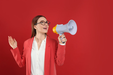 Young woman with megaphone on red background. Space for text