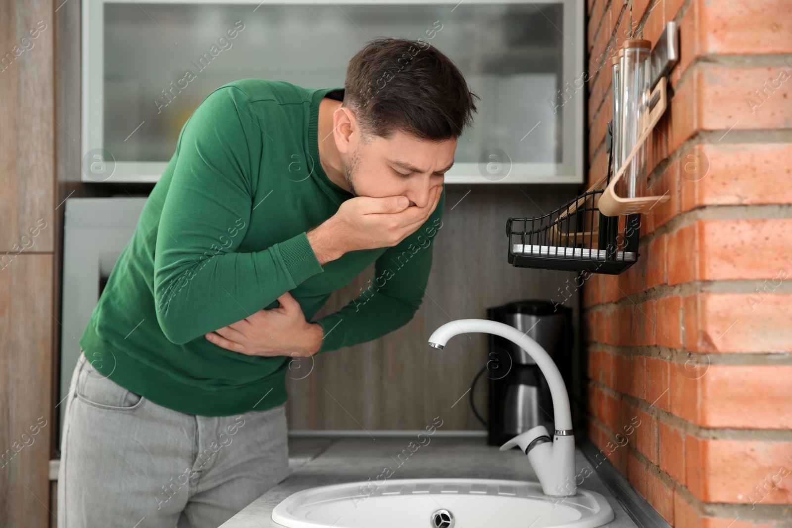 Photo of Young man having nausea in kitchen. Feeling sick