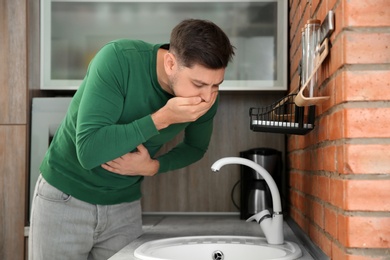 Young man having nausea in kitchen. Feeling sick