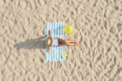 Image of Woman sunbathing on beach towel at sandy coast, aerial view