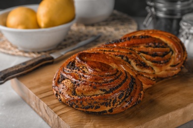 Photo of Tasty sweet bun with poppy seeds on gray table