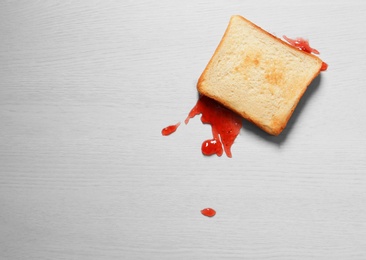 Photo of Overturned toast bread with jam on floor, top view