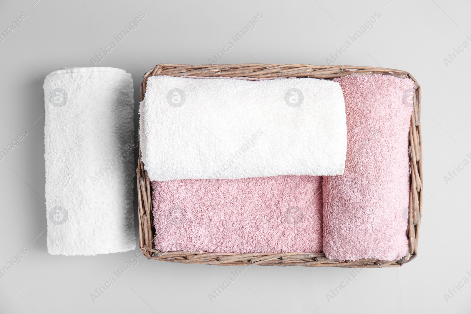 Photo of Basket with soft bath towels on grey background, top view