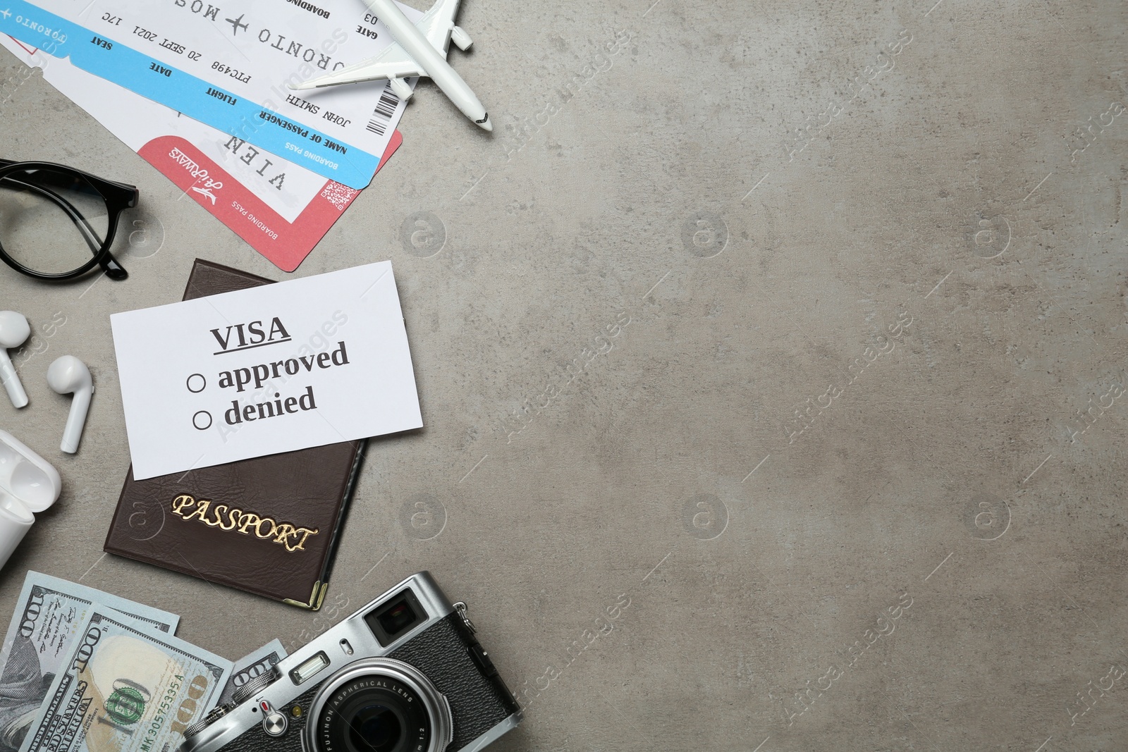 Photo of Flat lay composition with passport, toy plane and camera on grey table, space for text. Visa receiving